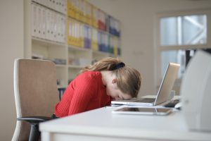 Een vrouw legt haar hoofd op haar laptop