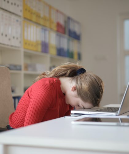 Een vrouw legt haar hoofd op haar laptop