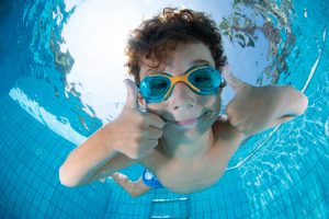 Jongetje zwemt onderwater met duimen omhoog