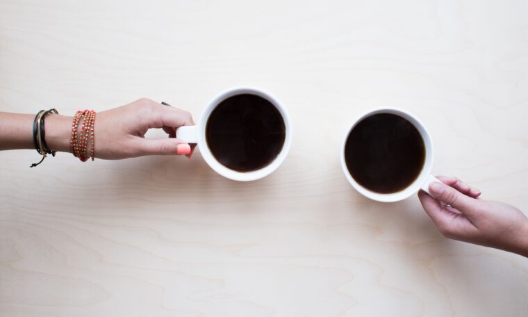 twee handen die een kop koffie vasthouden