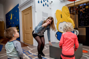 Vrouw geeft in het nijntje museum uitleg aan een kind met een CI