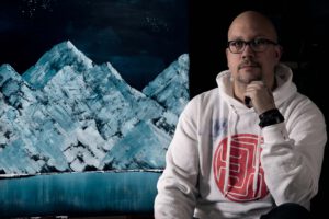 Dennis Hardes naast zijn schilderij van een ijsberg
