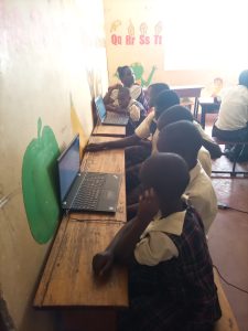 Een groepje kinderen zit aan een tafel naar een laptop te kijken