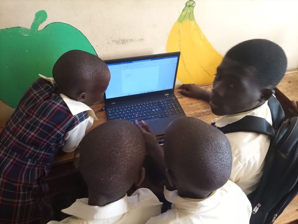 Vier kinderen kijken vol aandacht naar een laptop waarop een Wordocument met enkele woorden te zien is