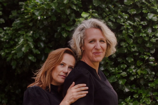 Twee vrouwen leunen liefdevol tegen elkaar aan