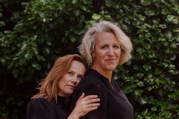 Twee vrouwen leunen liefdevol tegen elkaar aan