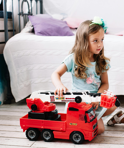 Jong meisje speelt met rode brandweerwagen die geluid maakt