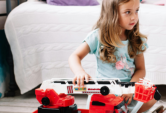 Jong meisje speelt met rode brandweerwagen die geluid maakt