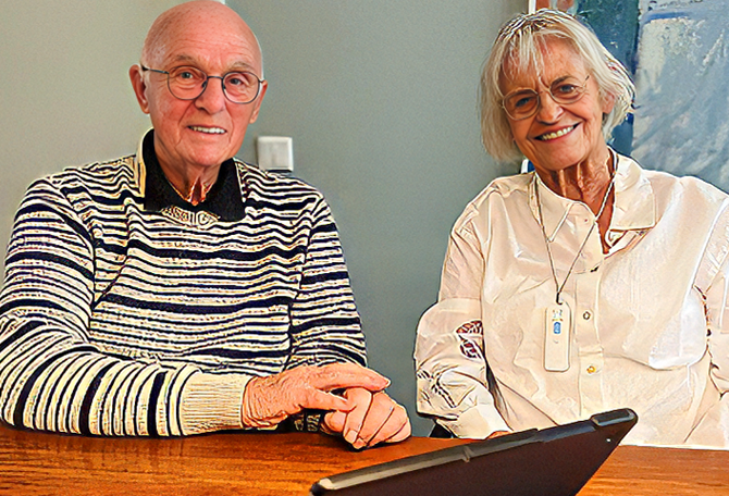 Bejaarde man en vrouw zitten aan tafel met een ipad voor hun