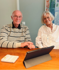 Bejaarde man en vrouw zitten aan tafel met een ipad voor hun