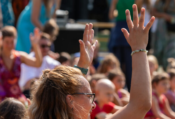 Groep mensen die handen in de lucht steken.