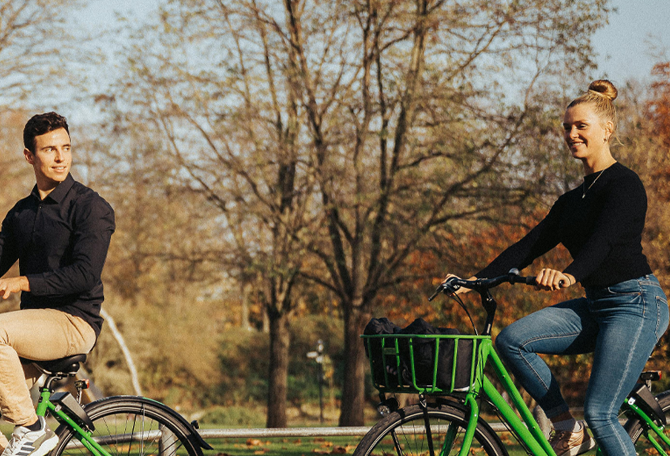 Man en vrouw op fietsen, fietsen door een park