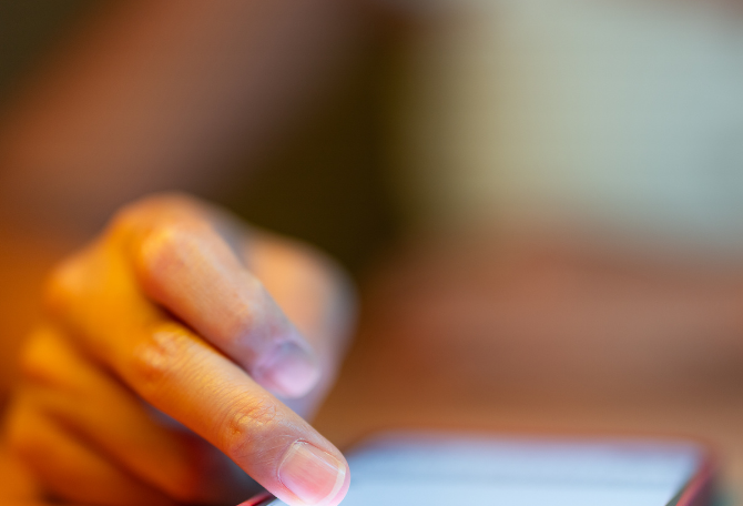 Mobiel op tafel en een hand die scrollt.