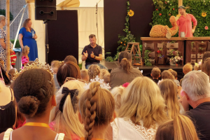 Verkleedde kinderen kijken naar een poppenspeler met tolk ngt ernaast