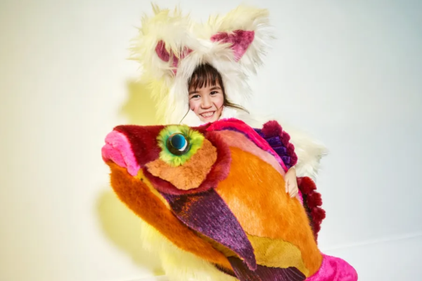 Meisje verkleed als pluche poes, met een knuffelvis in haar handen