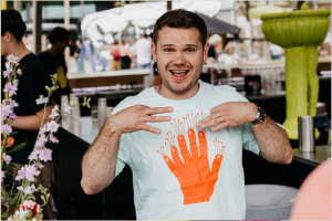 Man die 'gezellig' gebaart. Wit shirt met een oranje hand erop.