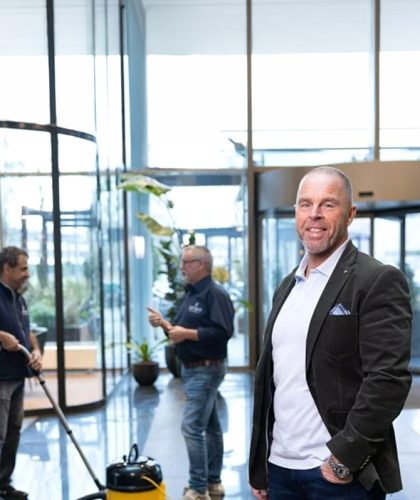 Man in pak staat voor schoonmaak team