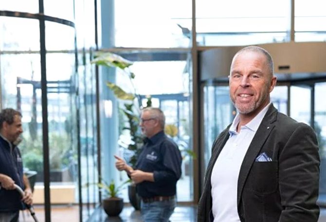 Man in pak staat voor schoonmaak team