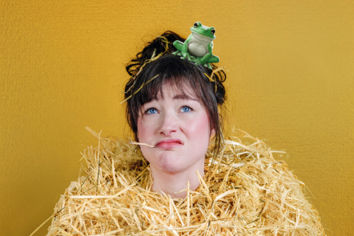 Vrouw in een hoop stro, met een kikker op hoofd