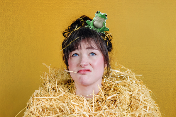 Vrouw in een hoop stro, met een kikker op hoofd